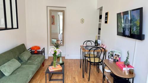 a living room with a green couch and a table at La Bulle Millésimée - à deux pas de la Gare et de l'Avenue de Champagne in Épernay