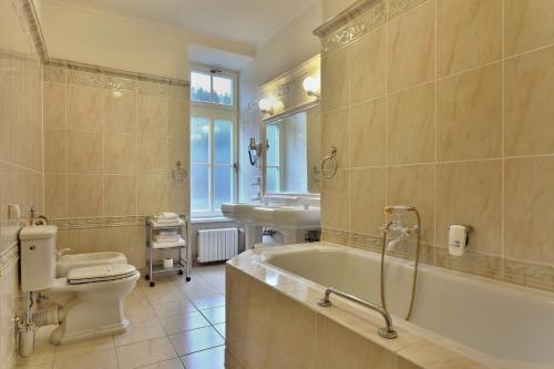 a bathroom with a tub and a toilet and a sink at Hotel Radium Palace in Jáchymov