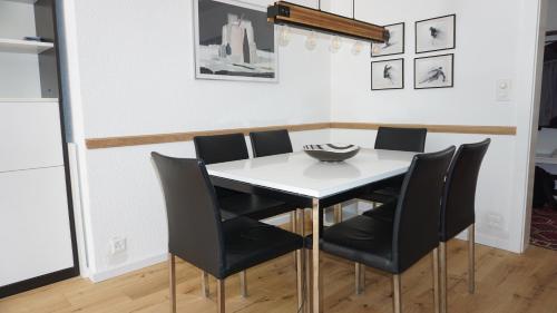 comedor con mesa blanca y sillas negras en Alpine Nest Crans-Montana, en Lens