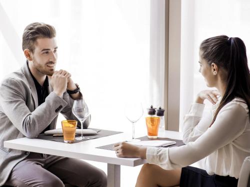 a man and woman sitting at a table with drinks at Novotel Chandigarh Tribune Chowk in Chandīgarh