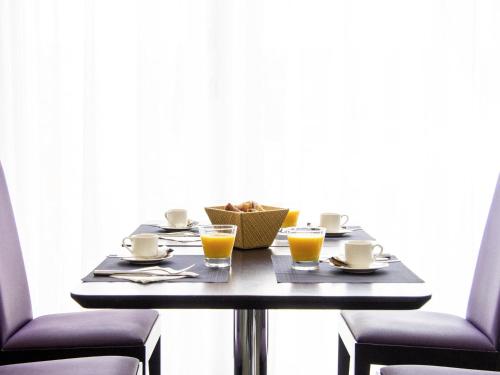 a table with two chairs and two glasses of orange juice at Novotel Chandigarh Tribune Chowk in Chandīgarh