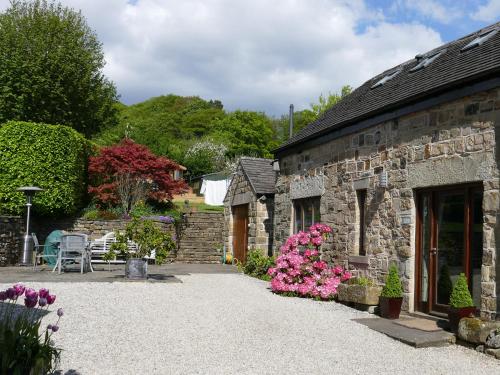 a stone building with pink flowers in front of it at Tick Tock Cottage in Baslow