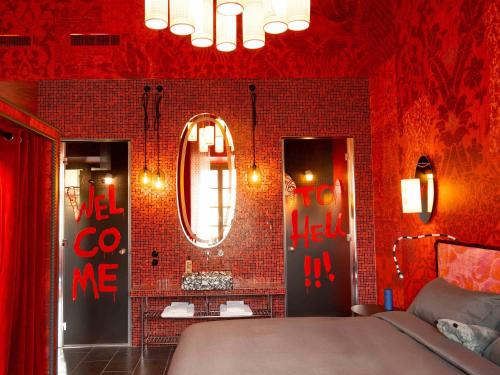 a red room with a bed and a mirror at 25hours Hotel Florence Piazza San Paolino in Florence