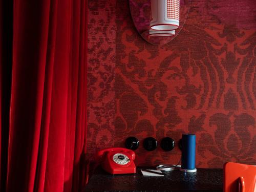 a red phone sitting on a table next to red curtains at 25hours Hotel Florence Piazza San Paolino in Florence