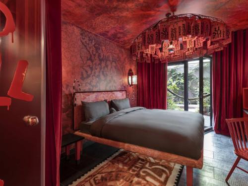 a bedroom with a bed with red walls and a window at 25hours Hotel Florence Piazza San Paolino in Florence