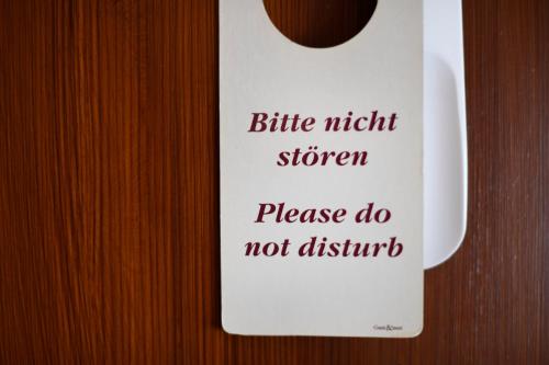 a white sign on a wooden door with a coffee cup at Hotel Marktkieker in Großburgwedel
