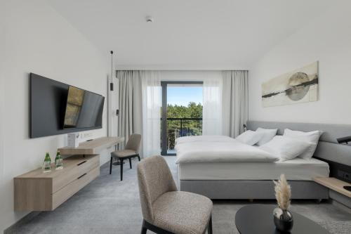 a white living room with a bed and a tv at Shellter Hotel Resort & Spa in Rogowo