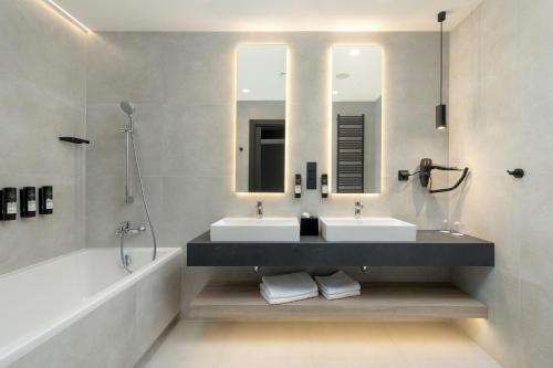 a bathroom with two sinks and a tub and a mirror at Shellter Hotel Resort & Spa in Rogowo