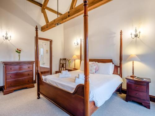 a bedroom with a four poster bed and a mirror at Woodpecker Barn - Cwl in Sculthorpe