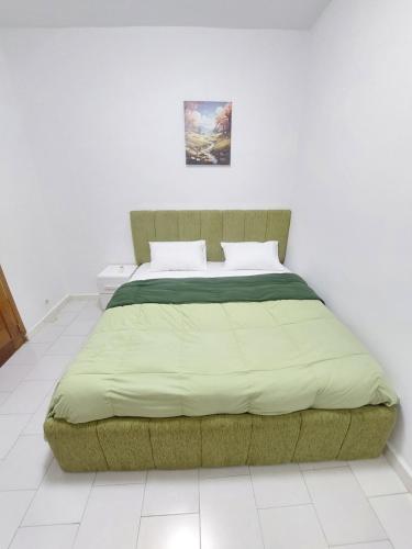 a bed in a white bedroom with a green blanket at Saphir in Dakar