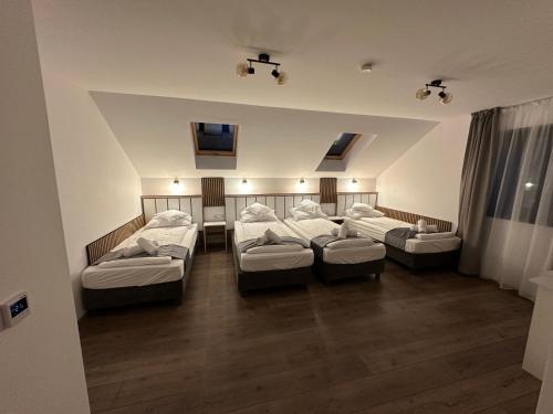 a room with three beds in a room with wood floors at Casa David Valea Avrigului in Avrig