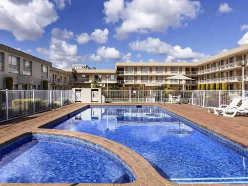 a swimming pool in front of a building at BreakFree Queanbeyan in Queanbeyan