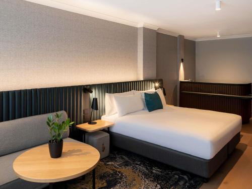 a hotel room with a bed and a couch at Novotel Sydney City Centre in Sydney
