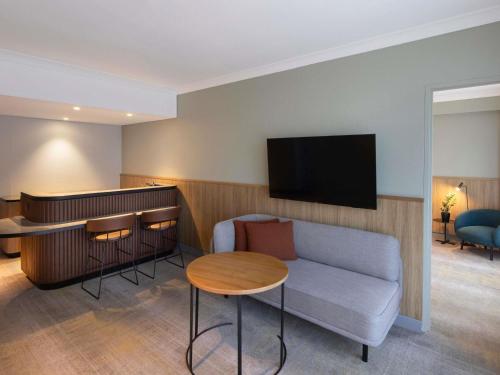a room with a couch and a table and a tv at Novotel Sydney City Centre in Sydney