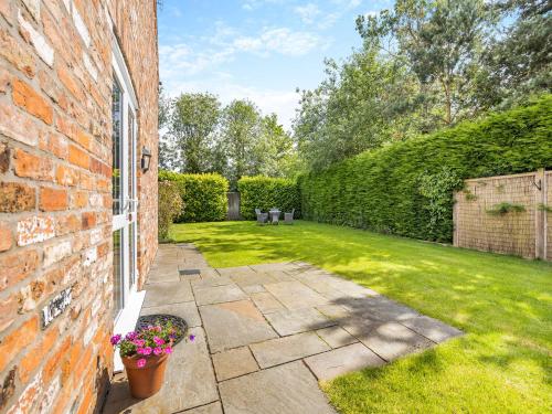 a garden with a brick wall and a patio at The Rose- Uk47155 in Burgh le Marsh