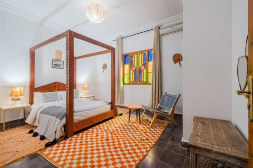 a bedroom with a canopy bed and a chair at Dar Salah - Eddine Oasis Pool & SPA in Oulad Mazoug