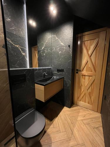 Un baño con lavabo y puerta de madera. en Apartamenty pod Tatrami, en Zakopane