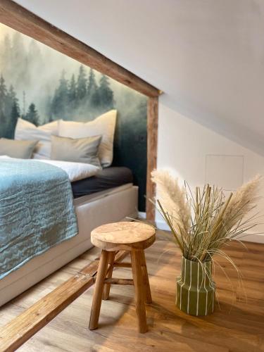 a bedroom with a bed and a wooden stool at Mellie's Ferienwohnung im Stryck in Willingen