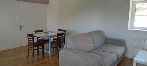 salon z kanapą, stołem i krzesłami w obiekcie La Maison de Jeanne w mieście Guainville