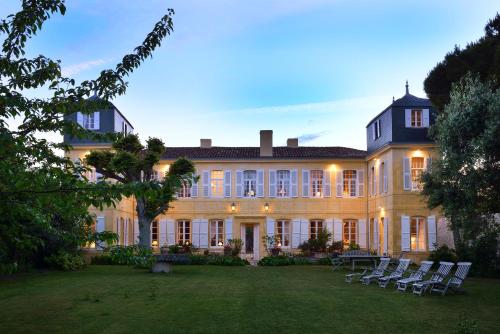 a large house with chairs in the yard at La Baronnie Hôtel & Spa - Teritoria in Saint-Martin-de-Ré