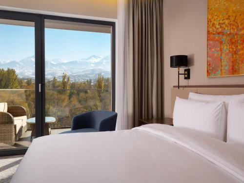 a hotel room with a bed and a large window at Swissôtel Wellness Resort Alatau Almaty in Almaty