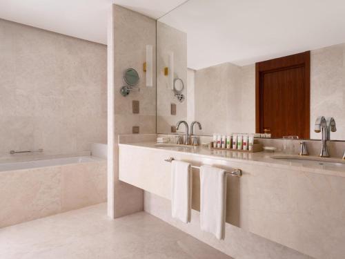 a white bathroom with two sinks and a bath tub at Swissôtel Wellness Resort Alatau Almaty in Almaty
