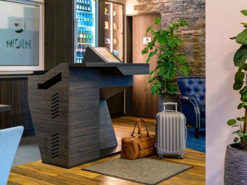 a lobby with a desk with a suitcase at ibis Styles Kiel City in Kiel
