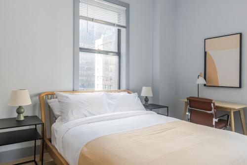 a bedroom with a bed and a desk and a window at Blueground Midtown West wd nr Central Park NYC-1996 in New York
