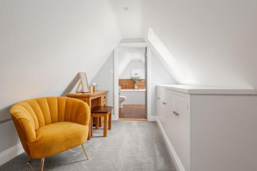 a living room with a yellow chair and a staircase at Forest Edge by Grandeur Property in Alderholt