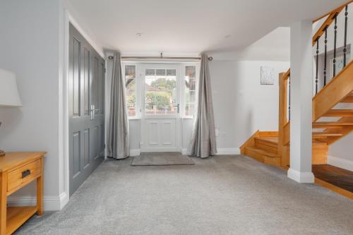 a hallway with a door and a window and stairs at Forest Edge by Grandeur Property in Alderholt