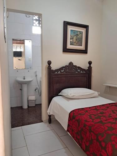 a bedroom with a bed and a bathroom with a sink at Hotel Pousada Acácia da Barra in Salvador