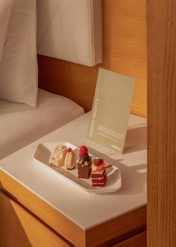 a plate of desserts sitting on a bed at Mövenpick Hotel & Apartments Ghala Muscat in Muscat