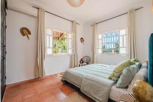 a bedroom with a large bed and two windows at Dar Salah - Eddine Oasis Pool & SPA in Oulad Mazoug