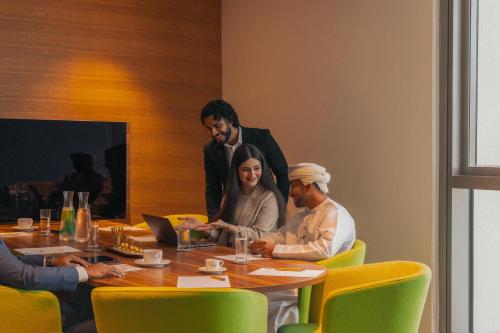 a group of people sitting around a table at Mövenpick Hotel & Apartments Ghala Muscat in Muscat