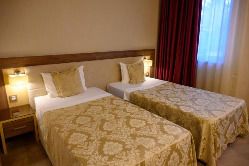 a hotel room with two beds and a window at Hotel Tami Residence in Niš