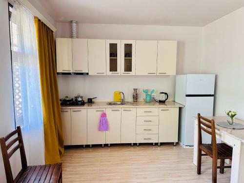 Una cocina con gabinetes blancos y un refrigerador blanco. en Boshuri Apartments, en Gori