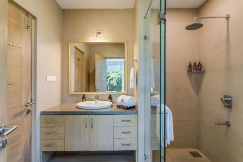 a bathroom with a sink and a shower with a mirror at Tastefully Done 1BHK Apartment by tisyastays in Candolim