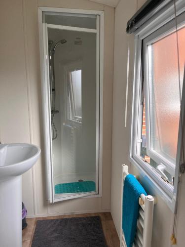 a bathroom with a shower and a sink and a window at Emerald Escape, Filey in Filey