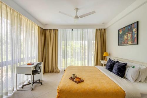 a hotel room with a bed and a desk and windows at Tastefully Done 1BHK Apartment by tisyastays in Candolim