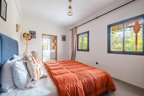 a bedroom with a bed with an orange comforter at Dar Salah - Eddine Oasis Pool & SPA in Oulad Mazoug