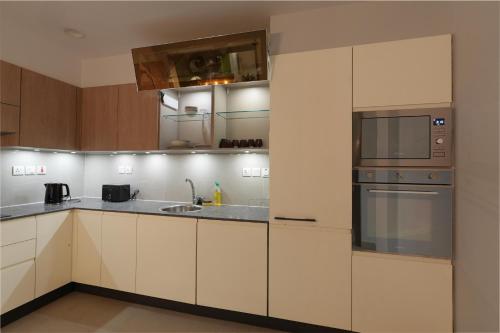 a kitchen with white cabinets and stainless steel appliances at Penta Square Executive Hotel Apartments City View DHA Lahore in Lahore