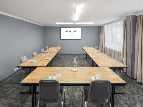 a conference room with wooden tables and chairs at Mercure Newcastle in Newcastle