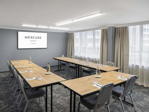 a meeting room with wooden tables and chairs at Mercure Newcastle in Newcastle