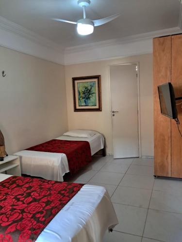 a hotel room with two beds and a flat screen tv at Hotel Pousada Acácia da Barra in Salvador