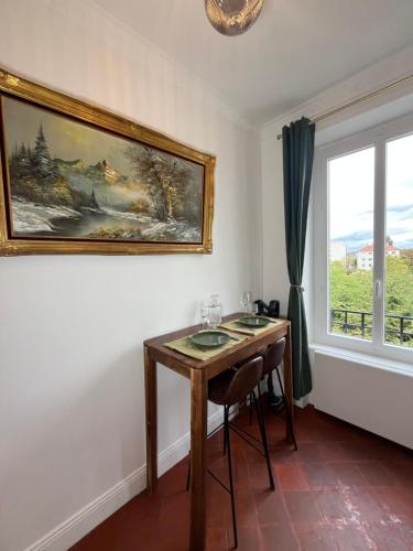 a dining room with a table and a painting on the wall at Appartement - Parking Gratuit - Métro in Villeurbanne