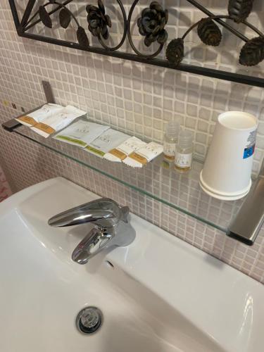 a bathroom sink with a mirror and a shelf above it at B&B Villa Lory in Fara Filiorum Petri