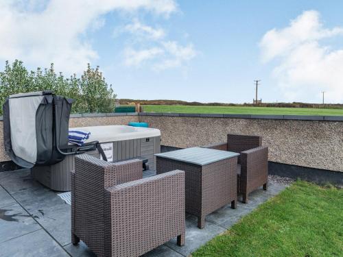 a patio with wicker chairs and a table and a tv at Ty Cwtch in Holyhead