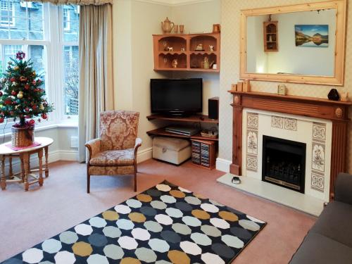 a living room with a fireplace and a christmas tree at Robinson in Keswick