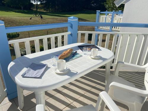 a white table with a plate of food on a deck at Cap sur les Dunes, appartement à Belle Dune in Fort-Mahon-Plage