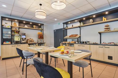 a restaurant with tables and chairs in a kitchen at Appart Hotel Odalys City Aix en Provence Les Floridianes in Aix-en-Provence